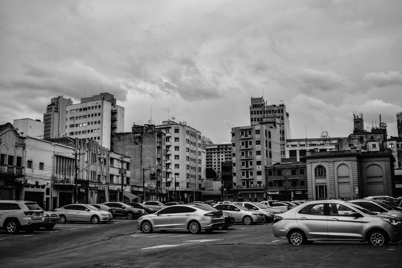 Carros estacionados em uma área urbana de São Paulo, em imagem em preto e branco.