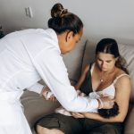 Profissional de saúde orienta mãe durante os cuidados com o bebê em uma visita domiciliar.