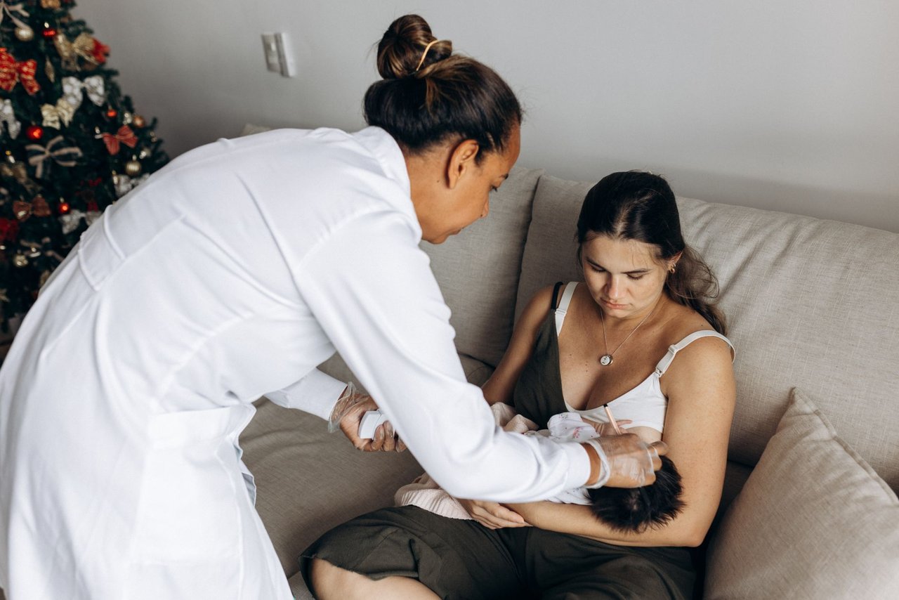 Profissional de saúde orienta mãe durante os cuidados com o bebê em uma visita domiciliar.