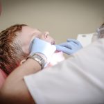 Dentista realiza avaliação odontológica em paciente durante atendimento em clínica.
